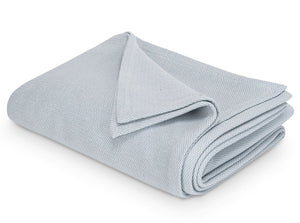 The Costa Mesa Blanket Collection by Matouk is displayed, featuring a neatly folded light grey blanket with a soft knitted texture on a white background.