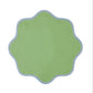 The Daisy Table Linen Collection by Duggan Society features a green, scalloped-edged design with a light blue border on white, evoking the look of elegant linen or scalloped edge napkins.