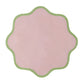 The Daisy Table Linen Collection by Duggan Society features a pink, scalloped-edged design with a green border, reminiscent of elegant table linens, set against a white background.