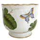 The Anna Weatherley Leaf Cachepot is a white porcelain piece with gold trim, featuring hand-painted green leaves and a blue-yellow butterfly—a stunning example of Hungarian artistry.