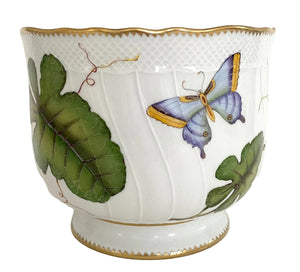 The Anna Weatherley Leaf Cachepot is a white porcelain piece with gold trim, featuring hand-painted green leaves and a blue-yellow butterfly—a stunning example of Hungarian artistry.