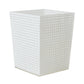 The Kim Seybert White Reed Bath Collection features a white, square wastebasket with a perforated circular pattern inspired by a wicker cane design.