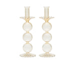 The Kim Seybert Iris Tall Candle Holder Set features two hand-blown glass candlesticks with a ribbed texture, three stacked spheres, and scalloped bases, shown against a white background.
