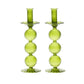 The Kim Seybert Iris Tall Candle Holder Set features two hand-blown green glass holders with stacked spheres and scalloped bases, displayed side by side on a white background.