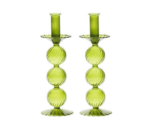 The Kim Seybert Iris Tall Candle Holder Set features two hand-blown green glass holders with stacked spheres and scalloped bases, displayed side by side on a white background.