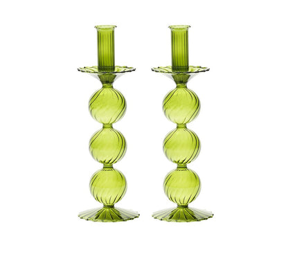 The Kim Seybert Iris Tall Candle Holder Set features two hand-blown green glass holders with stacked spheres and scalloped bases, displayed side by side on a white background.