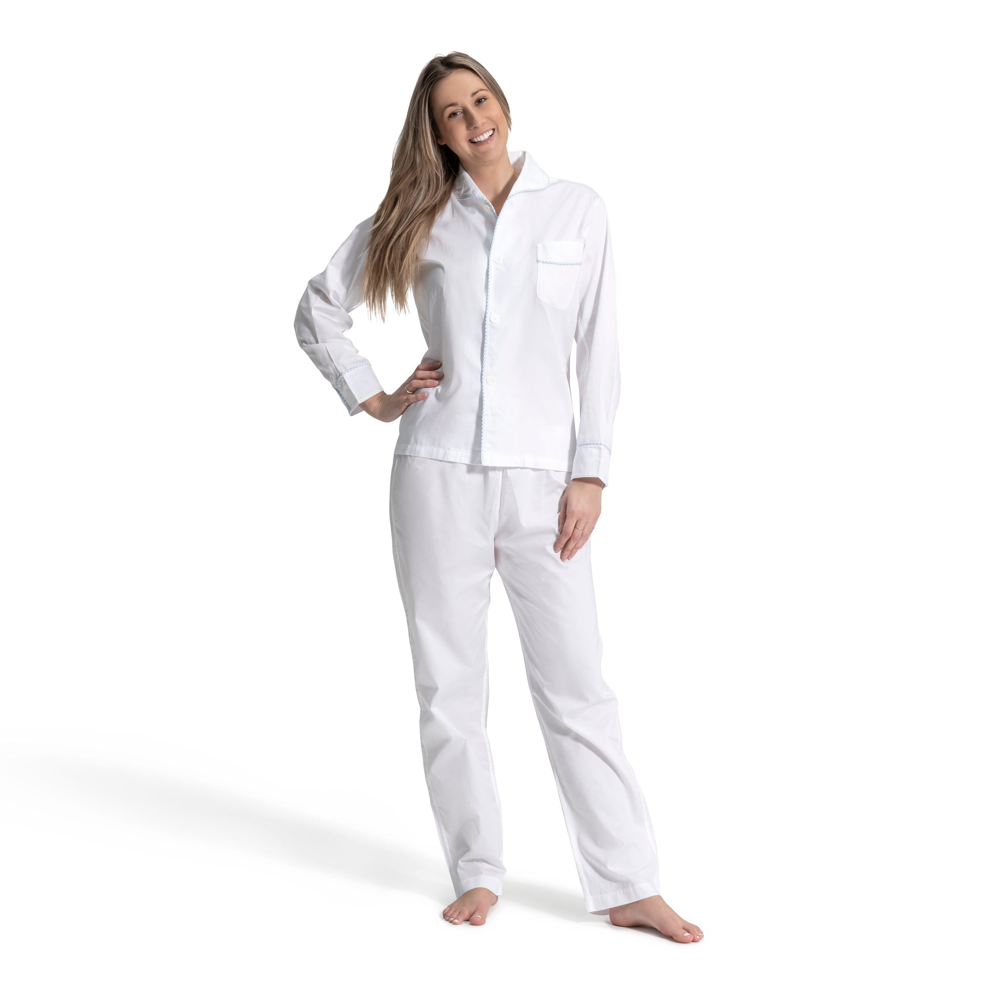 A woman stands barefoot on a white background, smiling at the camera in the Haute Home Smart Pajama Pant Set, embodying effortless luxury sleep style.