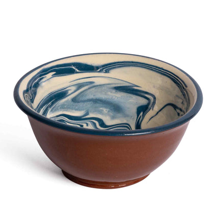 A ceramic bowl from the Marbre Serveware Collection by Sharland England showcases a brown exterior and a striking blue and cream marbled interior, displayed on a white background.