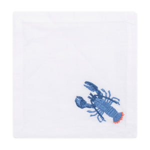 The Haute Home Lobster Blue Coaster Set includes 4 white linen coasters, each hand-embroidered with a blue and red lobster in the lower right corner.