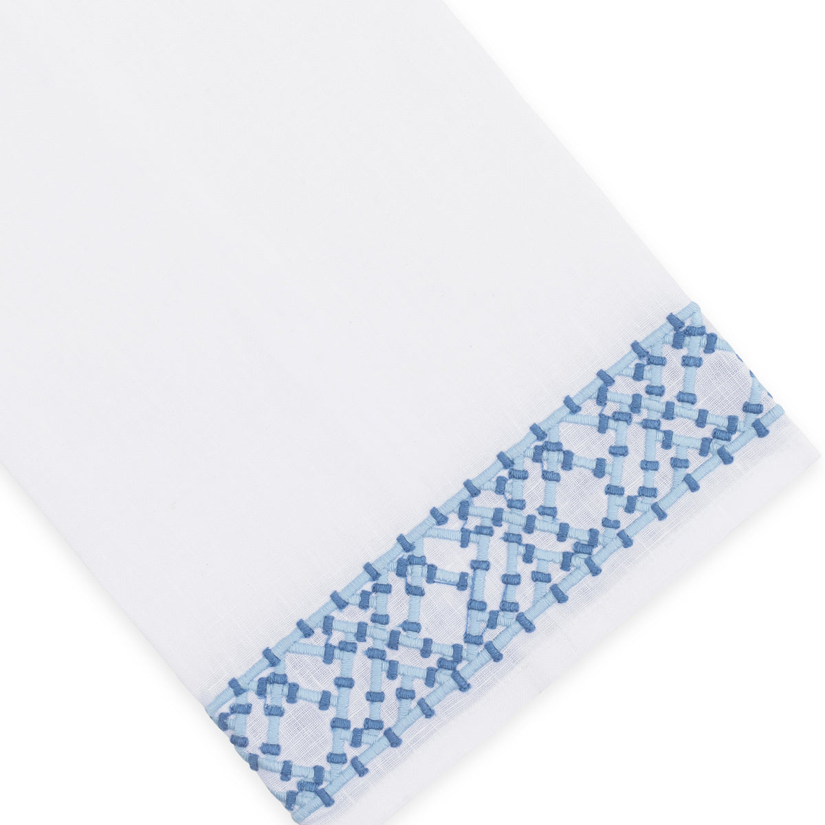 Presented at an angle on a plain background, the Haute Home Lido Bath Collection features premium white linen adorned with a blue geometric embroidered border near one edge—a timeless addition to elevate your home décor.