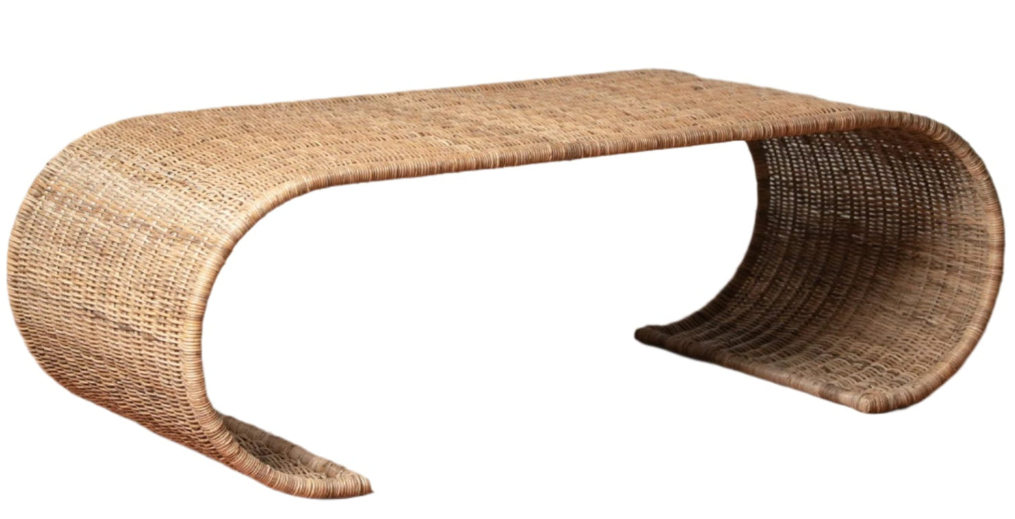 The Healdsburg Wicker Coffee Table by Selamat features a curved, continuous form with open arches at each end, crafted from sustainably harvested rattan for a stylish and eco-friendly centerpiece.