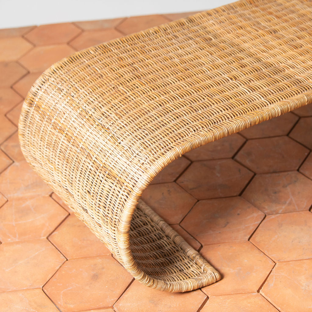 The Selamat Healdsburg Wicker Coffee Table, crafted from sustainably harvested rattan, rests on a floor of large hexagonal terracotta tiles.