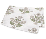 White fabric from the Dalila Bedding Collection by Matouk, featuring a vibrant green and beige floral print reminiscent of a Schumacher block print, folded neatly on a flat surface.