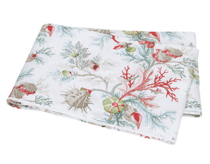 The Del Tesoro Bedding Collection by Matouk features folded white fabric with a vibrant coral and seashell print in red, green, and beige tones, evoking an oceanic fantasy.
