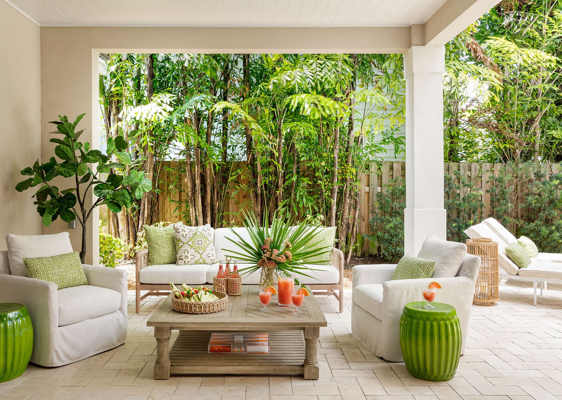 image of tropical patio setting with white sofa and chairs, green pillows and green garden stools