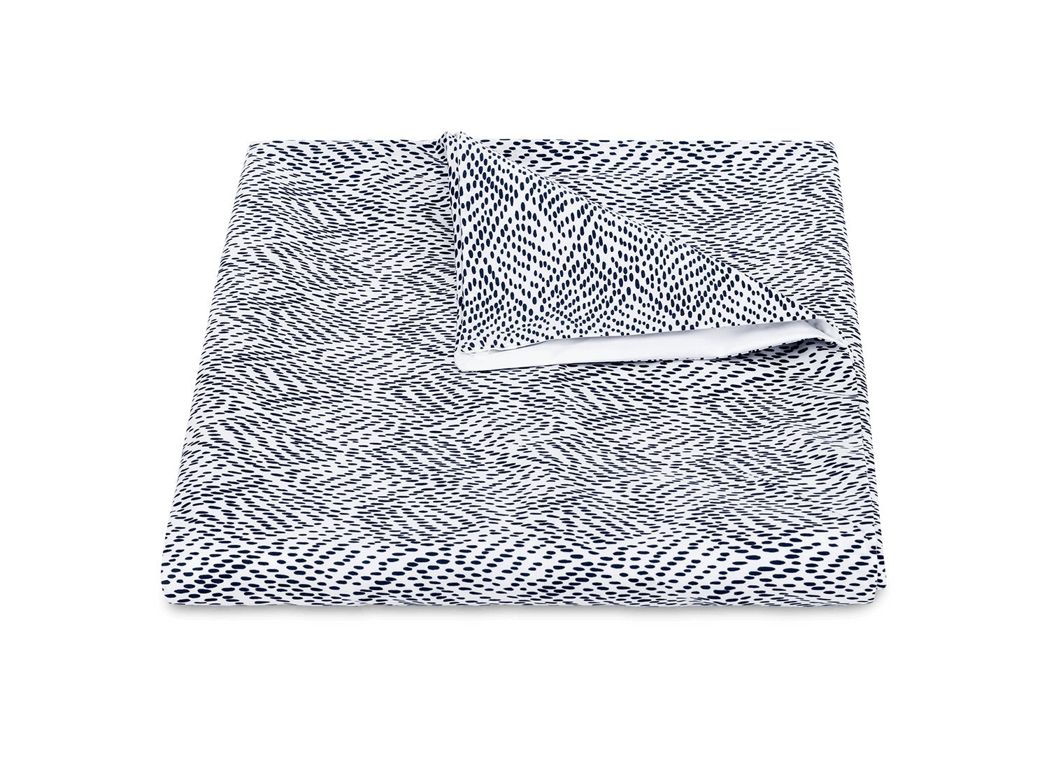 A folded white blanket from the Duma Diamond Bedding Collection by Matouk, featuring a navy blue dotted harlequin pattern and crafted from luxurious Egyptian cotton percale, displayed against a plain white background.