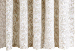 The Duma Diamond Dune Shower Curtain by Matouk features a beige and white geometric pattern inspired by Schumacher, hanging in soft, even folds.