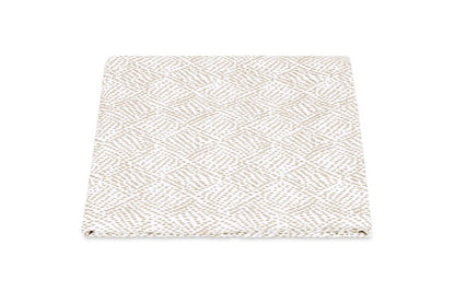 The Duma Diamond Bedding Collection by Matouk features a folded, beige and white textured fabric with a geometric diamond pattern in the Schumacher-inspired style, elegantly displayed on a white background.