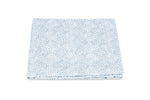 A folded cloth from the Duma Diamond Bedding Collection by Matouk, showcasing a striking white and blue geometric Schumacher-inspired pattern, is displayed against a plain white background.