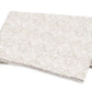Elevate your table setting with the Duma Diamond Bedding Collection by Matouk—a folded beige and white napkin featuring a subtle geometric pattern inspired by classic Schumacher designs, elegantly displayed on a pristine white background.