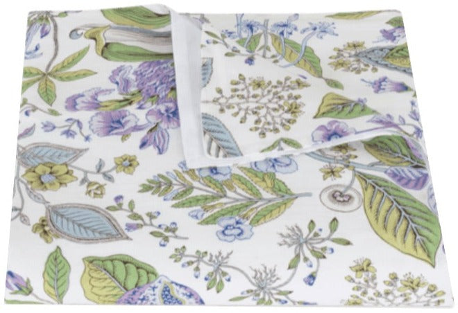 The Matouk Pomegranate Roman Linen Bedding Collection in Lilac features a folded napkin with green, blue, and purple botanical prints on white linen. OEKO-TEX Standard 100 certified for peace of mind.