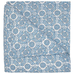The Sahil Indigo Bedding Collection by John Robshaw features a folded blanket with an intricate blue and white floral pattern, reminiscent of Mughal garden bedding, displayed on a white background.