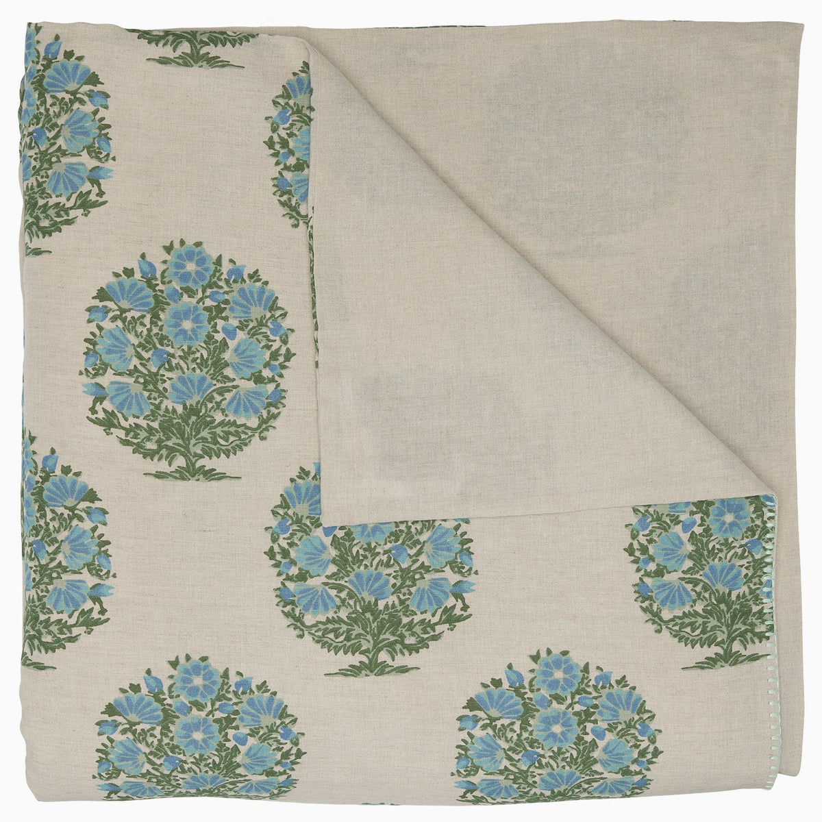 The Vani Leaf King Duvet Set by John Robshaw is crafted in a soft cotton linen blend inspired by Rajasthan palace bedding, featuring folded beige fabric adorned with green and blue floral bouquets and one corner turned to reveal the underside.