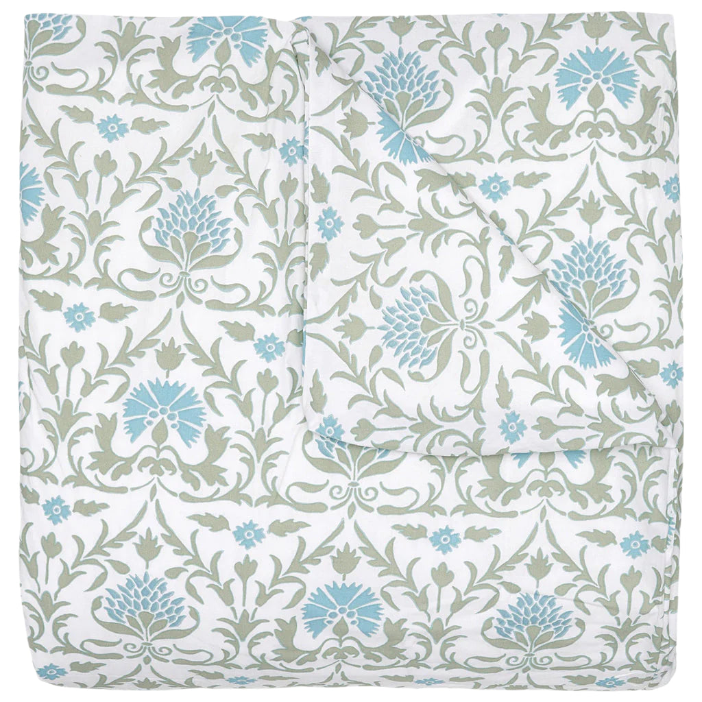 The Vidya Leaf Bedding Collection by John Robshaw is a folded quilt with a white background, featuring blue and sage floral and vine patterns inspired by a serene garden.