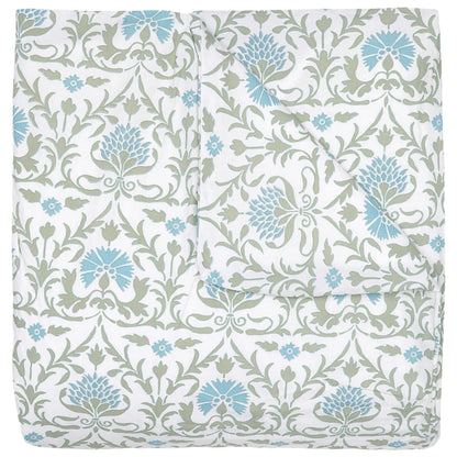 The Vidya Leaf Bedding Collection by John Robshaw is a folded quilt with a white background, featuring blue and sage floral and vine patterns inspired by a serene garden.
