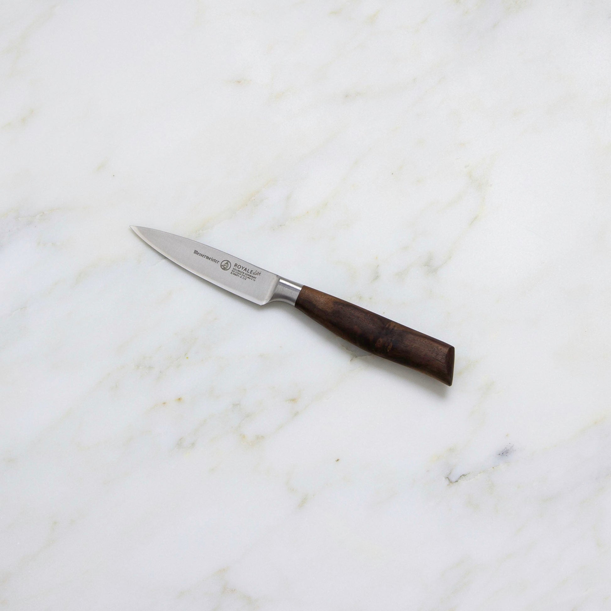 A Messermeister Royale Elite Knife Block Set, 5-Piece, featuring dark wooden handles and German stainless steel blades, is displayed on a white marble surface.
