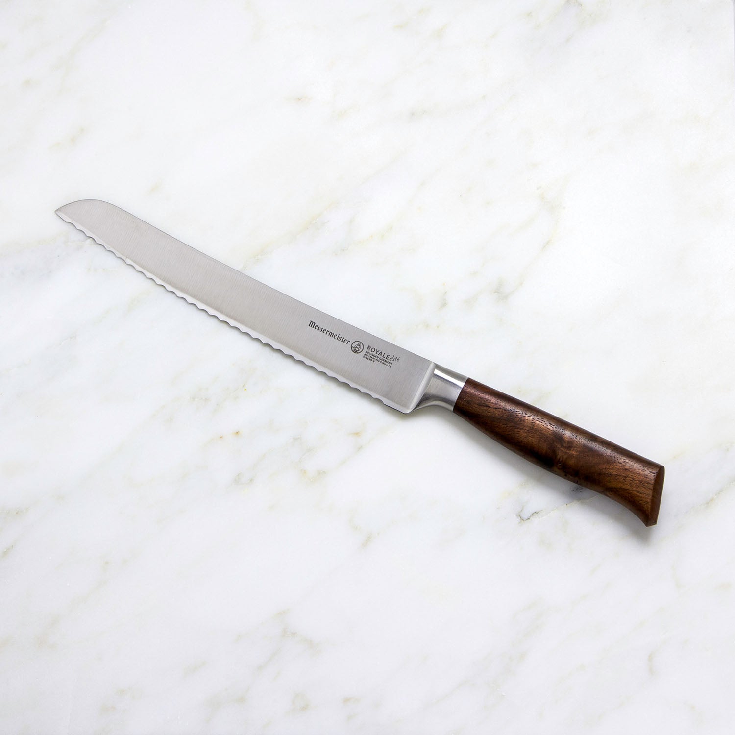 A Messermeister Royale Elite Knife Block Set, 5-Piece sits on a white marble surface, showcasing knives with German stainless steel blades and wooden handles.