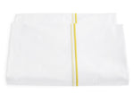From the Matouk Essex Bedding Collection, a folded white bedsheet with two parallel yellow stripes near the edge and elegant satin stitch embroidery is displayed against a plain white background.