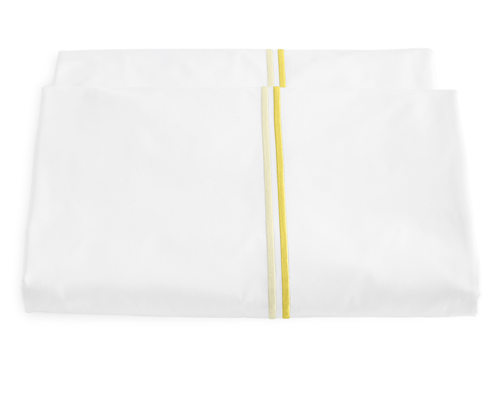 A folded white Matouk Essex Lemon Bedding Collection sheet with a yellow stripe down the center, evoking refined European hotel style, displayed on a plain background.