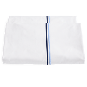 Two folded white sheets from the Matouk Essex Bedding Collection, Navy, featuring parallel blue and navy satin stitch embroidery near the edge, inspired by European hotel bedding, displayed on a plain white background.