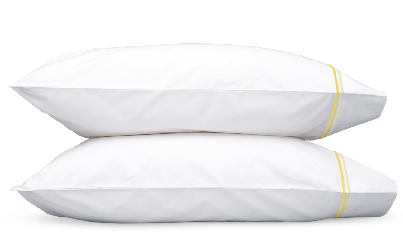 Two white pillows with yellow stripes from the Matouk Essex Lemon Bedding Collection are stacked against a plain background.