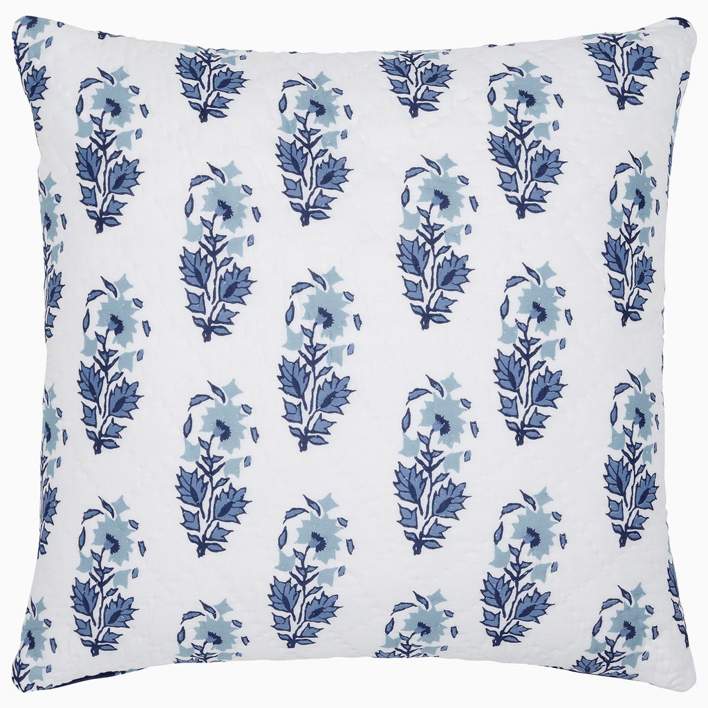 The Kanak Indigo Bedding Collection by John Robshaw features a square white pillow with a repeating indigo floral pattern inspired by traditional Indian block prints, crafted on hand-quilted cotton.