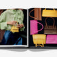 In Assouline's "Fashionphile: The Book of Iconic Bags," an open spread shows a person with a small yellow luxury accessory on the left and six colorful investment handbags on the right.