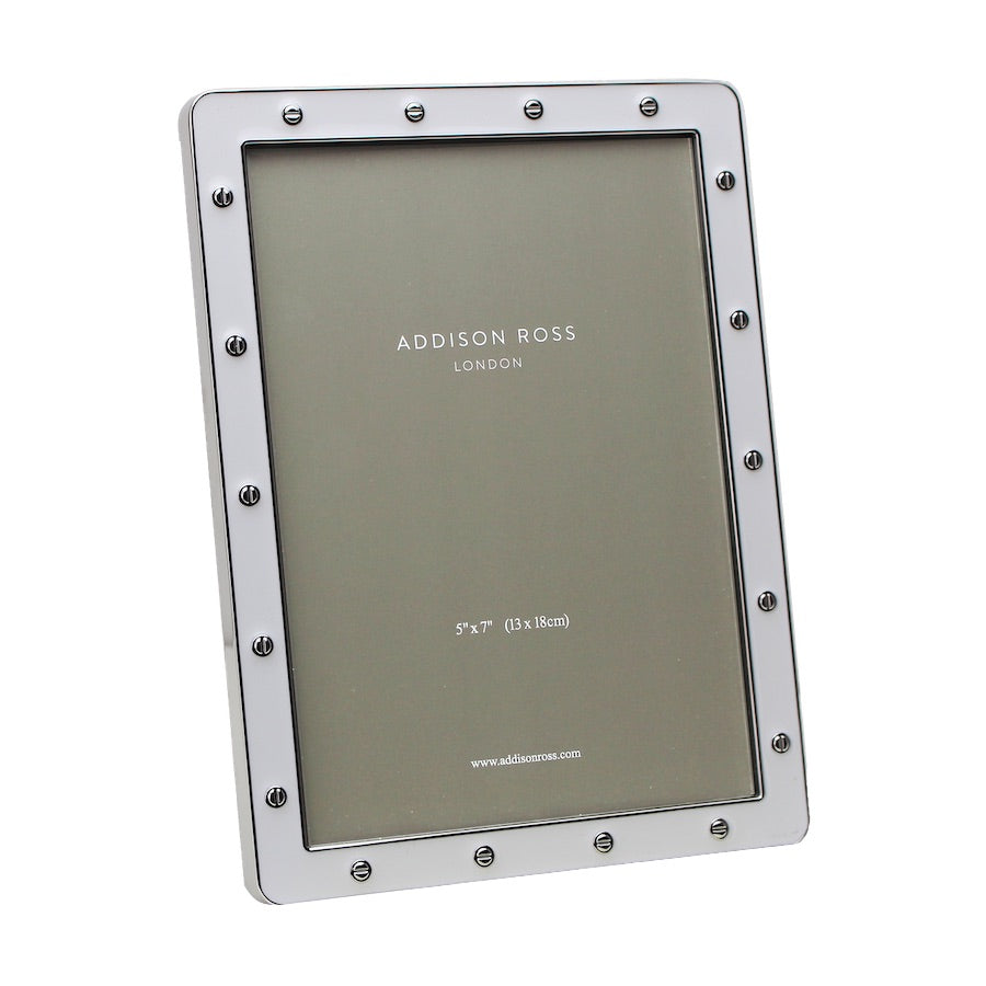 The Addison Ross Enamel Locket Frame Collection features a rectangular metal frame with screw-like details and a white enamel finish, designed to hold a 5x7 inch photo for upright display.