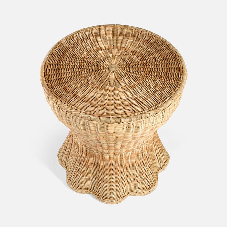 The Nevis Side Table by Made Goods features a round woven wicker design with a tapered silhouette and a flared, scalloped base, shown from above against a plain white background.