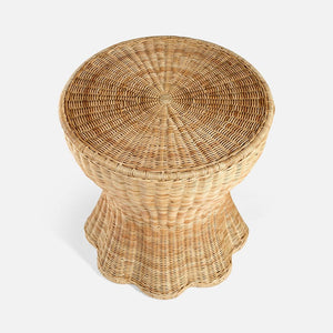 The Nevis Side Table by Made Goods features a round woven wicker design with a tapered silhouette and a flared, scalloped base, shown from above against a plain white background.