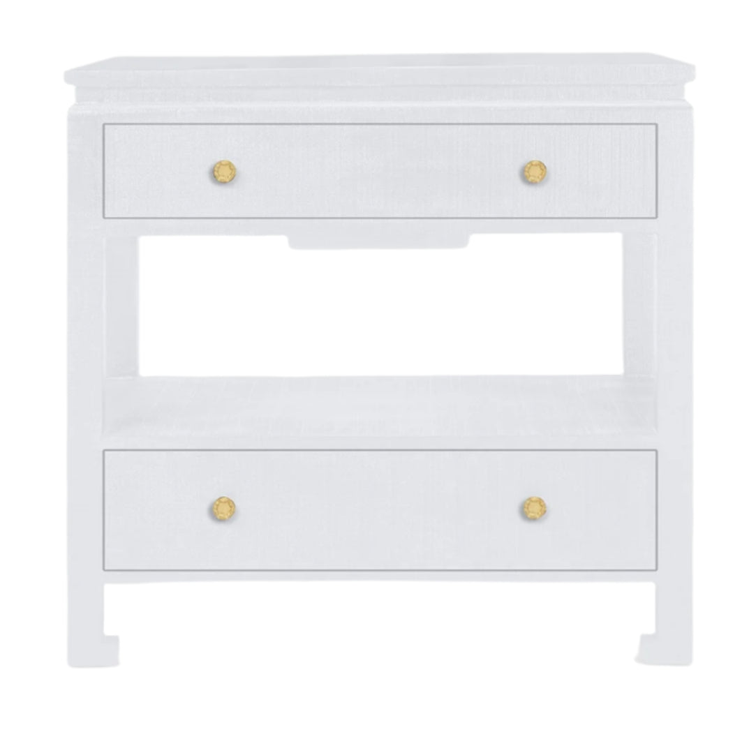 The Wylder Nightstand Collection by Made Goods features a sleek nightstand with three drawers, gold knobs, high gloss linen finish, and an open shelf between the drawers.