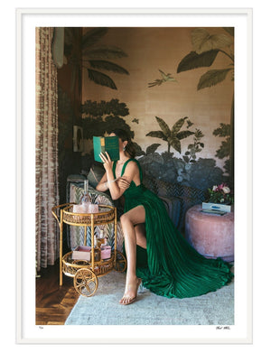 A woman in a green dress reads behind a book beside a bar cart, set against botanical wallpaper—Nick Mele Fine Art Kept Woman by Nick Mele Photography is perfect inspiration for signed and numbered artwork.