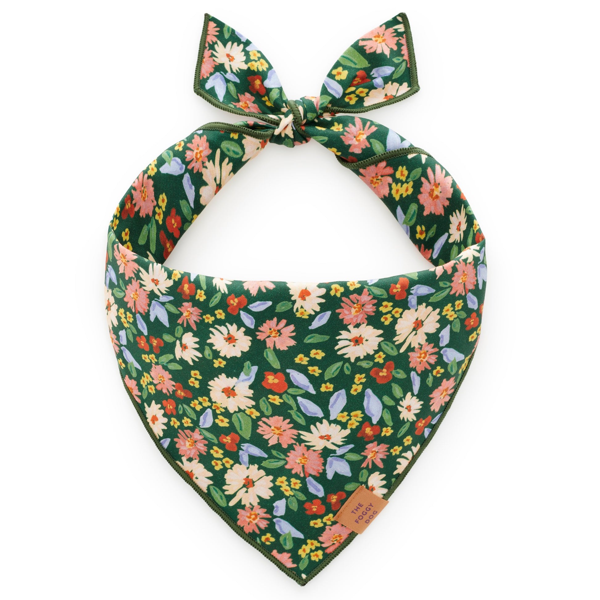 The Secret Garden Dog Bandana by Foggy Dog features a green base with a vibrant floral print of pink, orange, yellow, and white flowers accented by green leaves. It ties at the top for a stylish look.