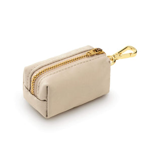 The Waste Bag Dispenser in Flax by The Foggy Dog is a small beige rectangular pouch featuring a gold zipper and gold metal clip, shown against a white background. This elegant accessory combines practicality and style, making it the perfect chic addition to your daily dog walks.