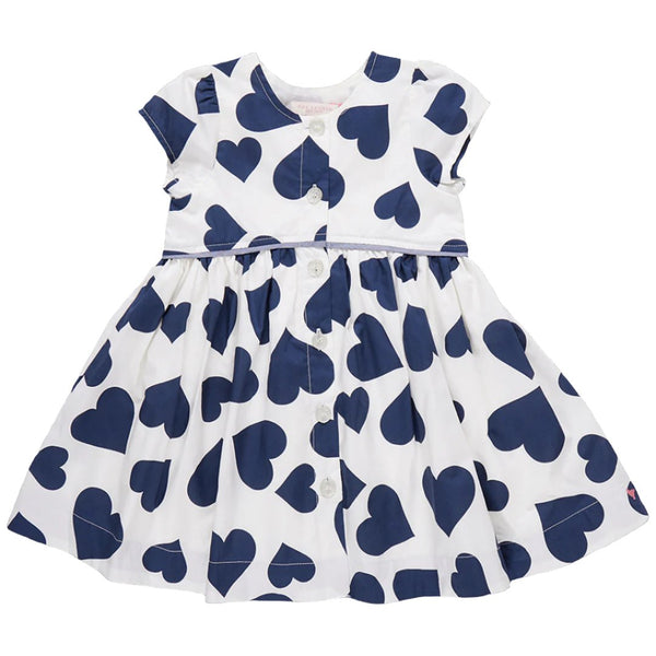 Introducing the Pink Chicken Girl's Fatima Dress: a charming white dress adorned with short sleeves and a striking large navy blue heart pattern. Enhanced with chambray detailing and glitter button closures, this piece is both playful and stylish for any young fashionista.