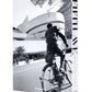 A black and white photo of a cyclist passing the Guggenheim Museum on New York’s iconic Fifth Avenue, featured on the cover of "5th Avenue," a history book by Assouline.