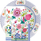 The Caspari Floral Porcelain Collection features a decorative plate and two overlapping triple-ply napkins, all adorned with vibrant pink, red, and green floral designs.