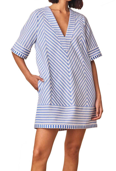 Woman in a coastal blue stripe Hunter Bell NYC Foster Dress made from yarn-dyed fabric, with short sleeves standing against a white background.