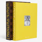 Two "From Louis to Vuitton" books by Assouline—one featuring a yellow cover and the other in a brown and gold Damier-style case—stand upright side by side.