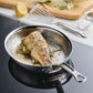 A whole fish tied with herbs and lemon slices cooks in the Hestan Provisions Oval Fish Pan on the stovetop, with a spatula, sliced fennel, lemon, salt, and pepper nearby—perfect for chef-style preparations.